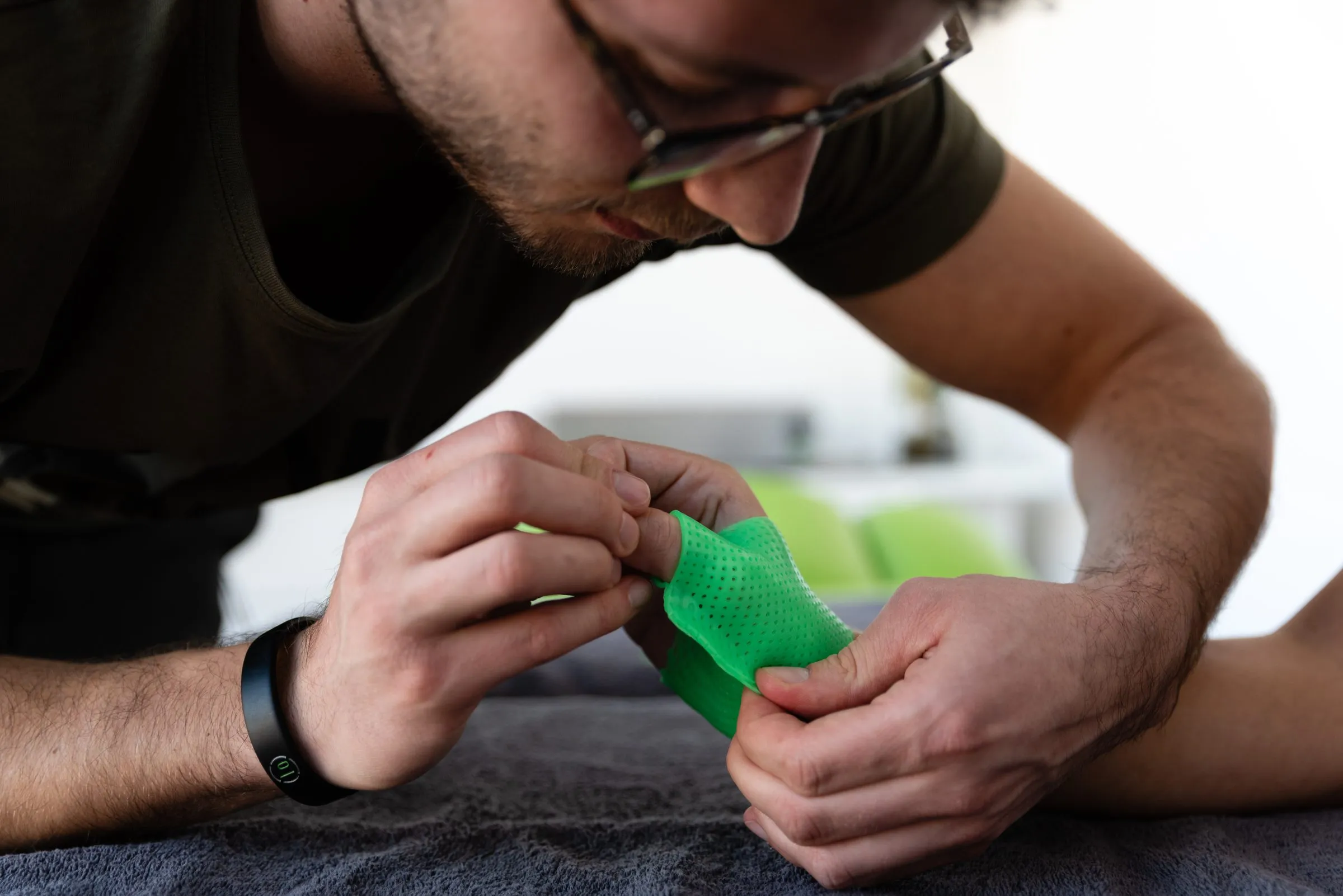 Ergotherapeut formt eine grüne Handschiene an der Hand einer Patientin