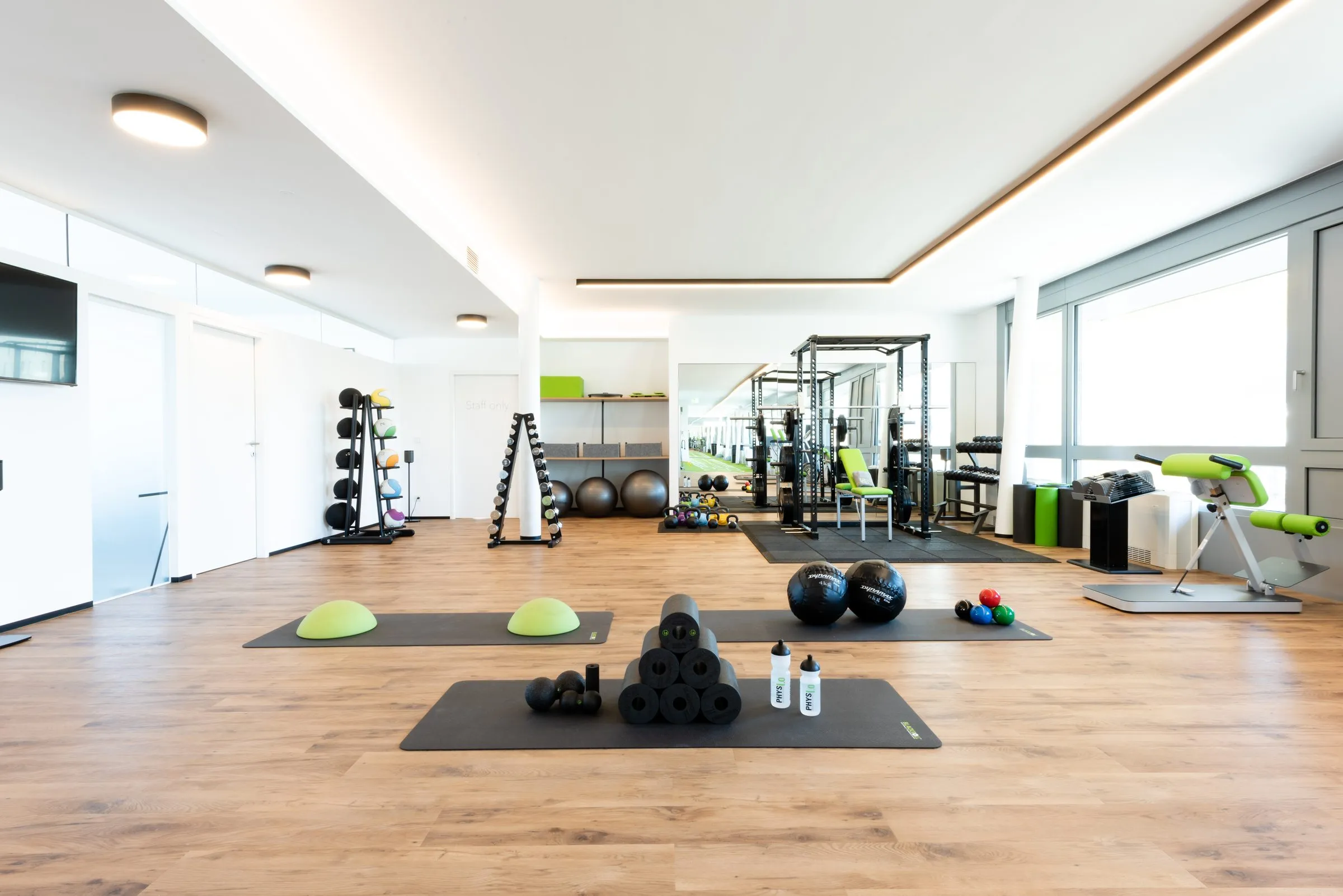 Heller Trainingsbereich der Praxis in Innsbruck mit Trainingsgeräten entlang der Fensterfront