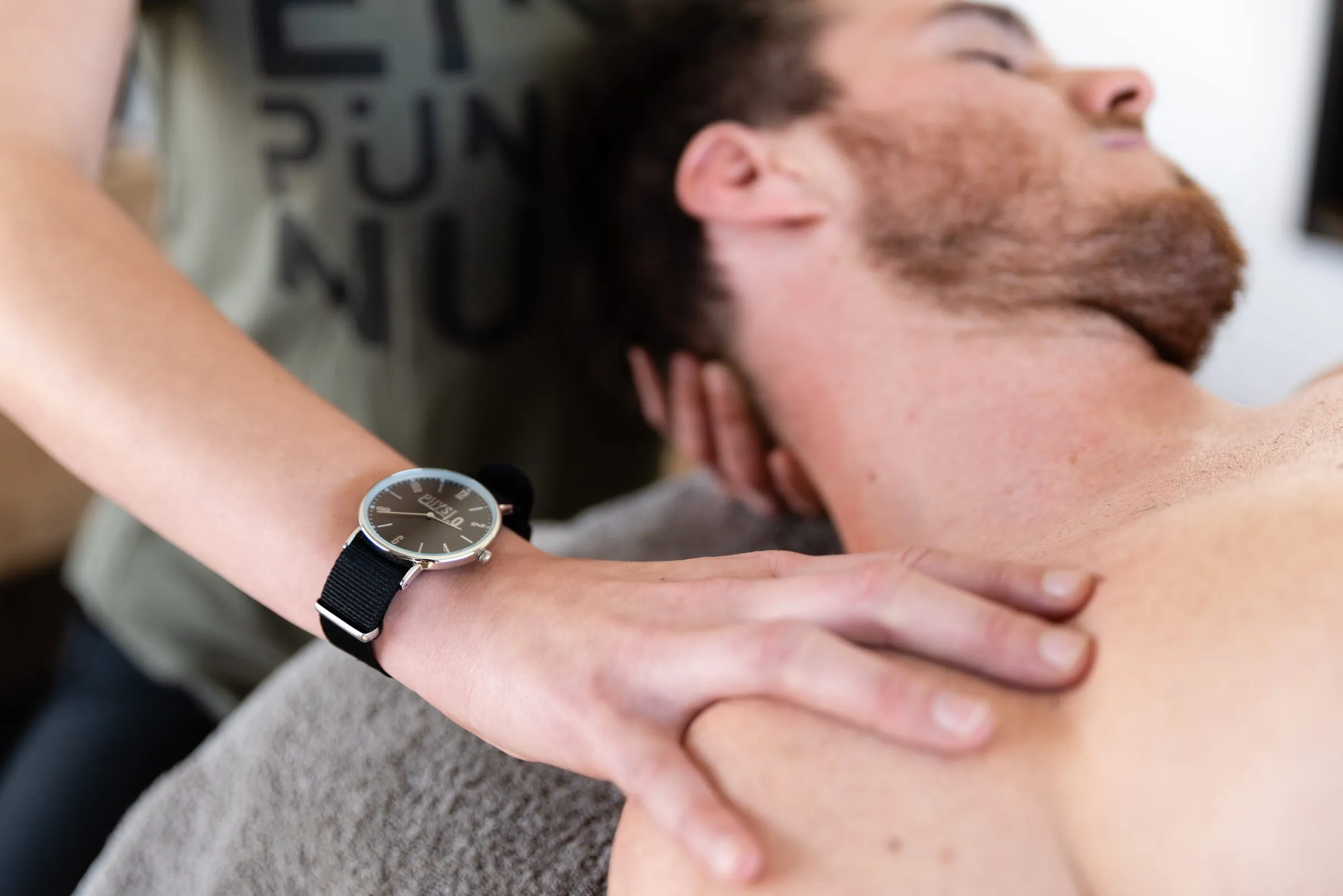 Hände einer Therapeutin am Nacken eines Patienten