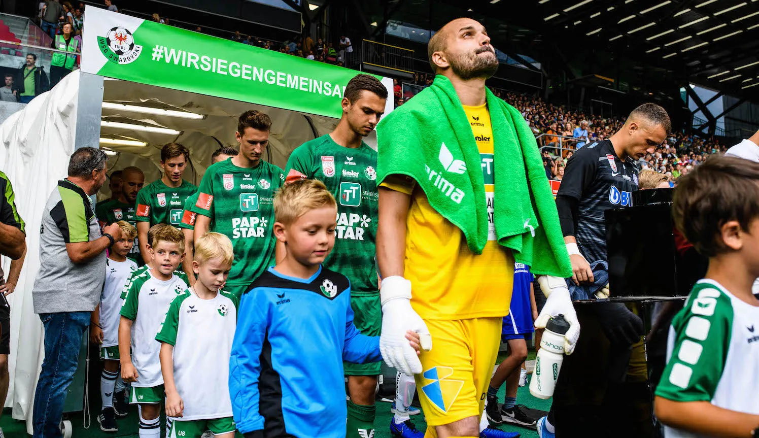 Spieler der WSG Tirol laufen mit Einlaufkindern ins Stadion ein